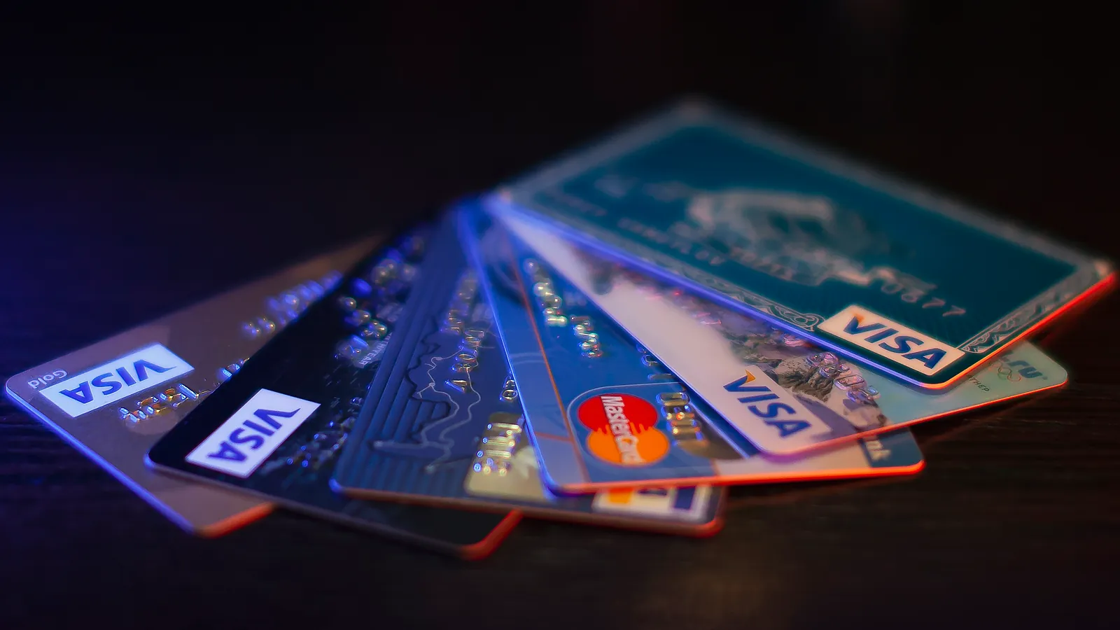 A fan of bank cards spread out on a dark table