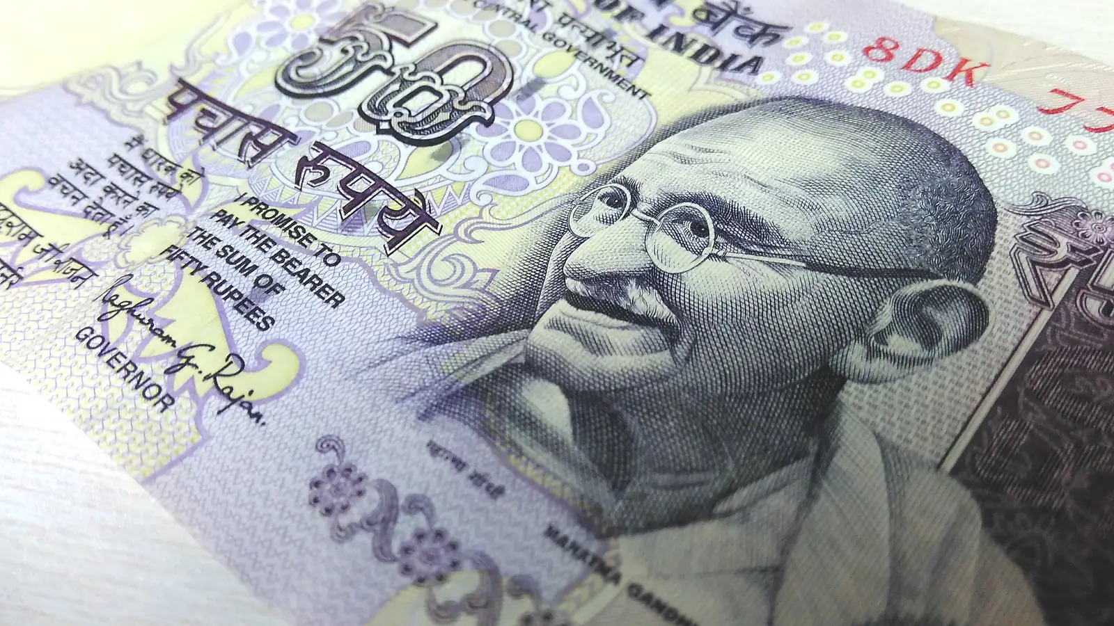 A close-up of an Indian fifty-rupee banknote showing the portrait of Mahatma Gandhi